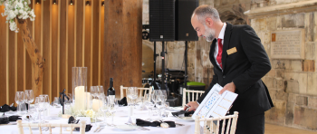 Staff member in suit setting up formal dining table at the Guildhall, York